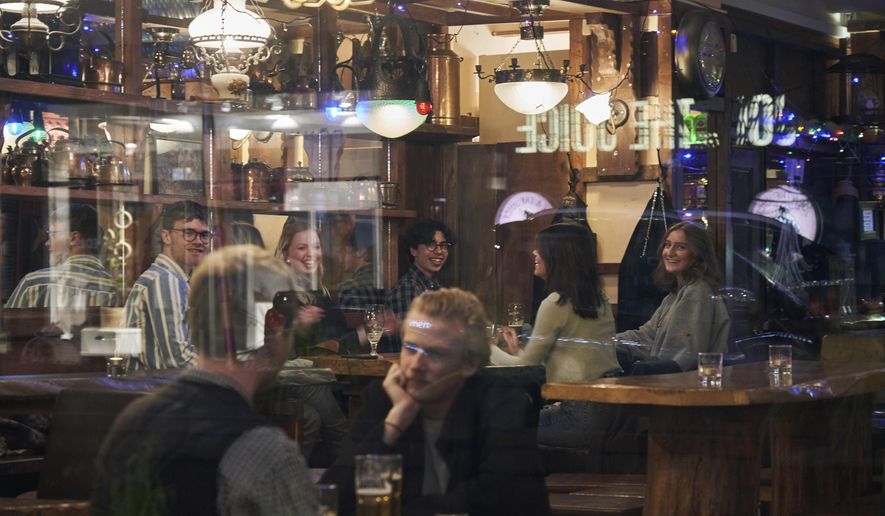 People sit in a bar in Stockholm, Sweden, on March 25, 2020. Sweden wants to cut red tape when it comes to dancing. The Swedish center-right coalition government wants to abolish a decade-old permit requirement, meaning the days of the so-called dance license is doomed. The proposal means that restaurants and nightclubs, among other places, no longer require approval from authorities to organize a dance performance. (AP Photo/David Keyton, File)