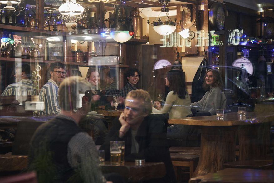 People sit in a bar in Stockholm, Sweden, on March 25, 2020. Sweden wants to cut red tape when it comes to dancing. The Swedish center-right coalition government wants to abolish a decade-old permit requirement, meaning the days of the so-called dance license is doomed. The proposal means that restaurants and nightclubs, among other places, no longer require approval from authorities to organize a dance performance. (AP Photo/David Keyton, File)