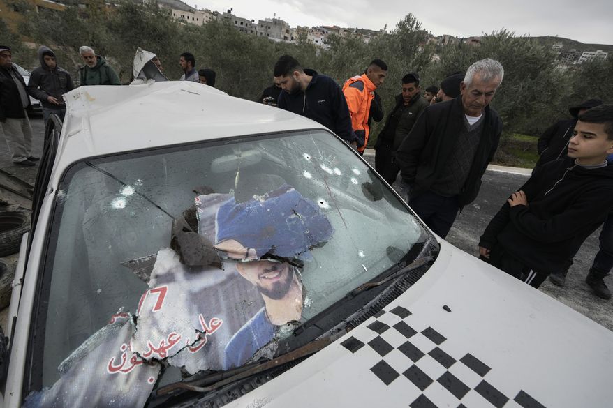Palestinians look at a damaged car following an Israeli raid in the West Bank village of Jaba, Saturday, Jan. 14, 2023. Palestinian medics say Israeli troops have shot and killed two Palestinian men during a military raid in the occupied West Bank, while a third man has died from wounds sustained in an earlier raid. (AP Photo/Majdi Mohammed)