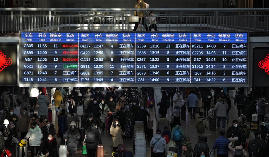 Travelers walk through a trains departure board at the West Railway Station in Beijing on Jan. 15, 2023. China has announced its first overall population decline in recent years amid an aging society and plunging birthrate. (AP Photo/Andy Wong, File)