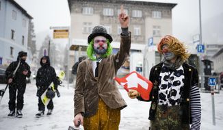 Two man made up as clowns attend a demonstration against the annual meeting of the World Economic Forum in Davos, Switzerland, Sunday, Jan. 15, 2023. The annual meeting of the World Economic Forum is taking place in Davos from Jan. 16 until Jan. 20, 2023. (AP Photo/Markus Schreiber)