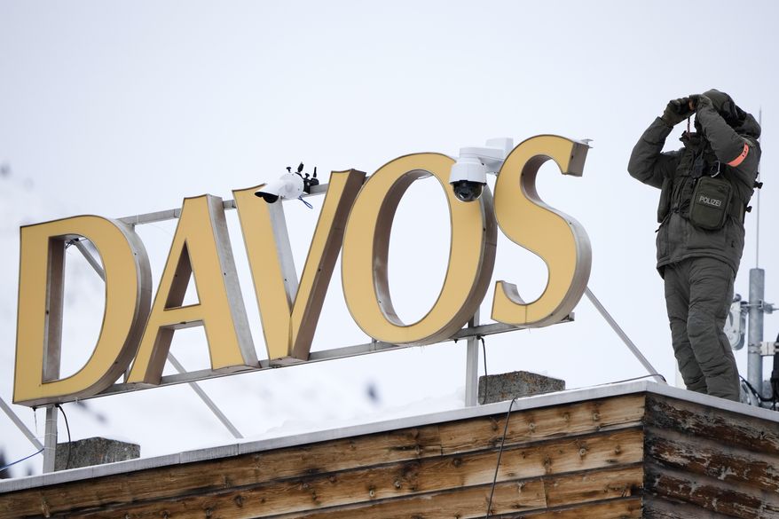 A police officer stands on the roof of a hotel and monitore the are with a binocular in Davos, Switzerland Monday, Jan. 16, 2023. The annual meeting of the World Economic Forum is taking place in Davos from Jan. 16 until Jan. 20, 2023. (AP Photo/Markus Schreiber)
