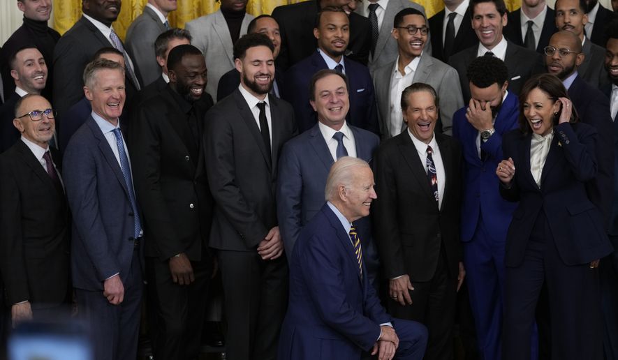 Vice President Kamala Harris reacts with other team members as President Joe Biden kneels for a group photo as they welcomes the 2022 NBA champions, the Golden State Warriors, to the East Room of the White House in Washington, Tuesday, Jan 17, 2023. (AP Photo/Susan Walsh)