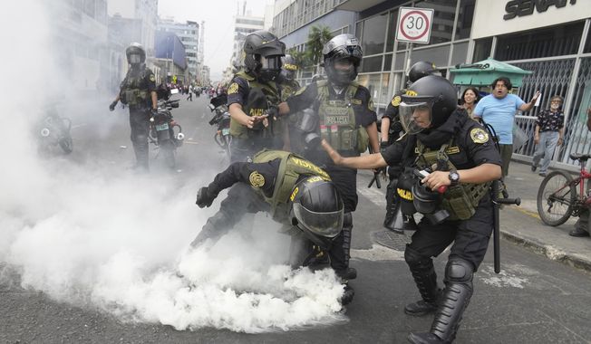 Police officers pick up a tear gas canister that was thrown back at them by anti-government protesters who traveled to the capital from across the country to march against Peruvian President Dina Boluarte in Lima, Peru, Wednesday, Jan. 18, 2023. Protesters are seeking immediate elections, Boluarte&#x27;s resignation, the release of ousted President Pedro Castillo and justice for the dozens of protesters killed in clashes with police. (AP Photo/Martin Mejia)