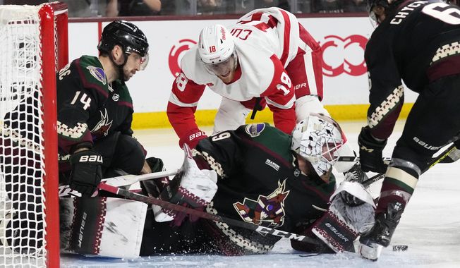 Arizona Coyotes goaltender Connor Ingram, middle, makes a save on shot by Detroit Red Wings center Andrew Copp (18) as Coyotes defensemen Shayne Gostisbehere (14) and Jakob Chychrun (6) help out during the second period of an NHL hockey game in Tempe, Ariz., Tuesday, Jan. 17, 2023. (AP Photo/Ross D. Franklin)