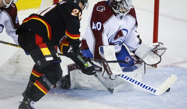 Colorado Avalanche goalie Alexandar Georgiev, right, gets his stick on the puck before Calgary Flames forward Blake Coleman can during the third period of an NHL hockey game Wednesday, Jan. 18, 2023, in Calgary, Alberta. (Jeff McIntosh/The Canadian Press via AP)