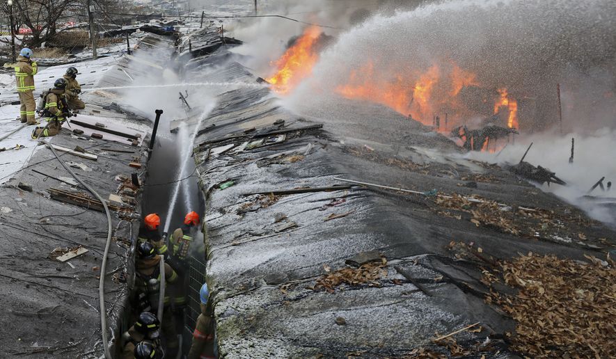 Firefighters battle a fire at Guryong village in Seoul, South Korea, Friday, Jan. 20, 2023. About 500 South Koreans were forced to flee their homes after a fire spread through a low-income neighborhood in southern Seoul on Friday morning and destroyed dozens of homes.  (Baek Dong-hyun/Newsis via AP)