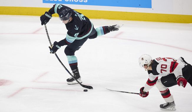 Seattle Kraken center Ryan Donato (9) shoots and scores with New Jersey Devils center Jesper Boqvist (70) defending during the second period of an NHL hockey game, Thursday, Jan. 19, 2023, in Seattle. (AP Photo/John Froschauer)
