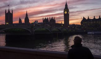 A man walks along the south bank of the River Thames backdropped by the Elizabeth Tower, known as Big Ben, of the Houses of Parliament, in London, Tuesday, Jan. 17, 2023. (AP Photo/Kin Cheung)