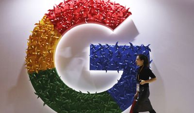 In this Monday, Nov. 5, 2018 file photo, a woman walks past the logo for Google at the China International Import Expo in Shanghai.  (AP Photo/Ng Han Guan, File)