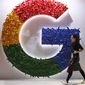 In this Monday, Nov. 5, 2018 file photo, a woman walks past the logo for Google at the China International Import Expo in Shanghai.  (AP Photo/Ng Han Guan, File)