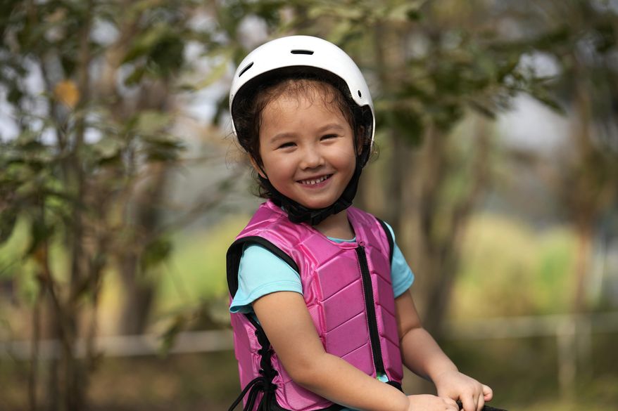 Rylae-Ann Poulin smiles as she learns to ride a horse in Bangkok, Thailand, Saturday, Jan. 14, 2023. Rylae-Ann was among the first to benefit from a new way of delivering gene therapy — directly into the brain — that experts believe holds great promise for treating a host of brain disorders. (AP Photo/Sakchai Lalit)