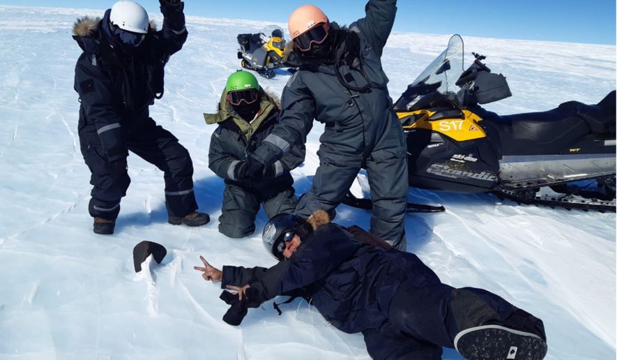 Researchers Maria Schönbächler (wearing a white helmet), Maria Valdes (green helmet), Vinciane Debaille (orange helmet) and Ryoga Maeda (black helmet) pose with a 16.7-pound meteorite in Antarctica. (Photo courtesy of Maria Valdes)