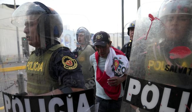 Police detain an anti-government protester in downtown Lima, Peru, Tuesday, Jan. 24, 2023. Protesters are seeking the resignation of President Dina Boluarte, the release from prison of ousted President Pedro Castillo, immediate elections and justice for demonstrators killed in clashes with police. (AP Photo/Martin Mejia)