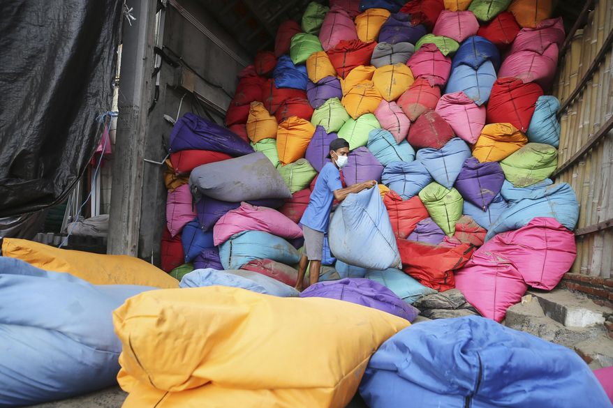 A man prepares beanbag at Kuta beach on the popular tourist island of Bali, Indonesia on Jan. 20, 2023. The beaches and temples of destinations like Bali and Chiang Mai are the busiest they have been since the pandemic struck three years ago, but they’re still relatively quiet. (AP Photo/Firdia Lisnawati)