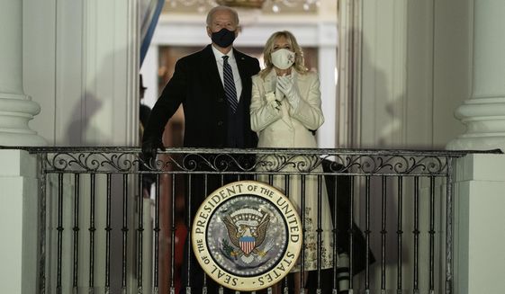 President Joe Biden and first lady Jill Biden watch fireworks from the White House, Jan. 20, 2021, in Washington. The ocean blue tweed dress and matching coat that Jill Biden wore for Joe Biden&#39;s presidential inauguration is about to go on display at the Smithsonian&#39;s National Museum of American History. In a rare move, the museum will also display the ensemble she wore for evening inaugural events, an ivory silk wool dress and matching cashmere coat. (AP Photo/Evan Vucci, File)