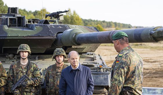 German Chancellor Olaf Scholz stands with German army Bundeswehr soldiers at a &quot;Leopard 2&quot; main battle tank during a training and instruction exercise in Ostenholz, Germany, Monday, Oct. 17, 2022. Scholz is expected to announce Wednesday, Jan. 25, 2023, that his government will approve supplying German-made battle tanks to Ukraine. (Moritz Frankenberg/dpa via AP, File)