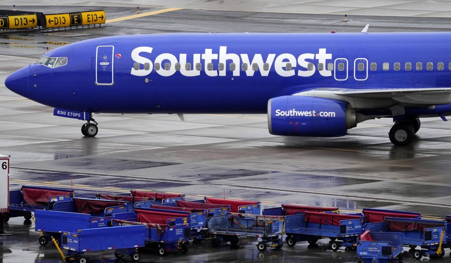 A Southwest Airlines jet passes unused luggage carts as it arrives, Dec. 28, 2022, at Sky Harbor International Airport in Phoenix. The U.S. Transportation Department said Wednesday, Jan. 25, 2023, it is investigating whether Southwest Airlines deceived customers by knowingly scheduling more flights in late December than it realistically could handle. (AP Photo/Matt York, File)