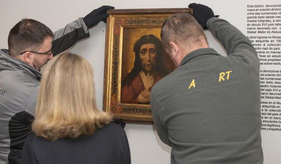 Two people take down the diptych of Ecce Homo after the signing of the act of restitution of the diptych of the Dolorosa and Ecce Homo to Poland at the Museum of Pontevedra in Pontevedra, northwestern Spain, Wednesday, Jan. 25, 2023. A museum in northwest Spain has returned two 15th-century paintings to Polish officials after it was determined that they were looted by the forces of Nazi Germany during World War II. (Gustavo de la Paz/Europa Press via AP)