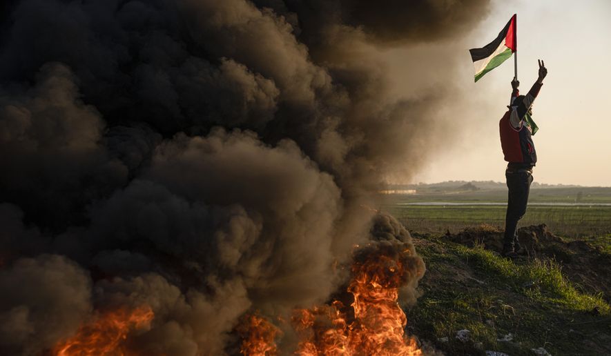 Palestinians burn tires and wave the national flag during a protest against Israeli military raid in the West Bank city of Jenin, along the border fence with Israel, in east of Gaza City, Thursday, Jan. 26, 2023. During the raid in the West Bank town of Jenin, Israeli forces killed at least nine Palestinians, including a 60-year-old woman, and wounded several others, Palestinian health officials said, in one of the deadliest days of fighting in years. The Israeli military said it was conducting an operation to arrest militants when a gun battle erupted. (AP Photo/Fatima Shbair)