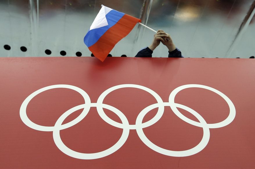 A Russian flag is held above the Olympic Rings at Adler Arena Skating Center during the Winter Olympics in Sochi, Russia on Feb. 18, 2014. Russia and its ally Belarus have been invited to compete at the Asian Games in the next step to qualify athletes for next years Paris Olympics. The arrangement has been brokered by the International Olympic Committee. The IOC indicated on Wednesday that it favours allowing Russians to compete at the 2024 Olympics as neutral athletes. (AP Photo/David J. Phillip, File)