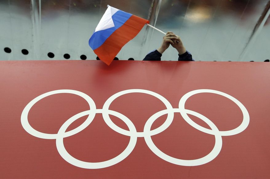 A Russian flag is held above the Olympic Rings at Adler Arena Skating Center during the Winter Olympics in Sochi, Russia on Feb. 18, 2014. Russia and its ally Belarus have been invited to compete at the Asian Games in the next step to qualify athletes for next year’s Paris Olympics. The arrangement has been brokered by the International Olympic Committee. The IOC indicated on Wednesday that it favours allowing Russians to compete at the 2024 Olympics as neutral athletes. (AP Photo/David J. Phillip, File)