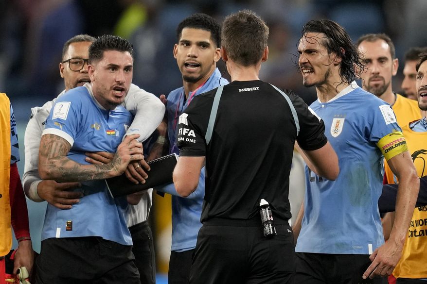 Uruguay's Edinson Cavani, right, argues with referee Daniel Siebert of Germany, at the end of a World Cup group H soccer match against Ghana at the Al Janoub Stadium in Al Wakrah, Qatar, on Dec. 2, 2022. FIFA banned Uruguay players Fernando Muslera and José María Giménez for four games each on Friday Jan. 27, 2023 for aggressively confronting match officials when the team was eliminated from the World Cup last month. Veterans Edinson Cavani and Diego Godín must also serve one-game bans when Uruguay next plays, FIFA said in announcing disciplinary verdicts. (AP Photo/Darko Vojinovic, File)