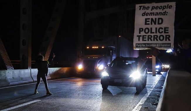 A demonstrator tries to stop traffic along the Interstate 95 bridge during a protest over the death of Tyre Nichols, Friday, Jan. 27, 2023, in Memphis, Tenn. Authorities released video footage Friday showing Nichols being beaten earlier this month by five Memphis police officers who held the Black motorist down and repeatedly struck him with their fists, boots and batons as he screamed for his mother. (Patrick Lantrip/Daily Memphian via AP)