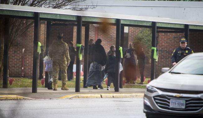 Parents escort their children to Richneck Elementary School on Monday, Jan. 30, 2023, in Newport News, Va. The Virginia elementary school where a 6-year-old boy shot his teacher has reopened with stepped-up security and a new administrator. (AP Photo/John C. Clark)