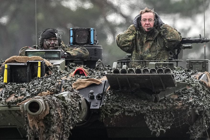 German Defense Minister Boris Pistorius, right, sits on a Leopard 2 tank at the Bundeswehr tank battalion 203 at the Field Marshal Rommel Barracks in Augustdorf, Germany, Wednesday, Feb. 1, 2023. After the government's decision to deliver fourteen Leopard 2 tanks to Ukraine, the capabilities of the Leopard 2A6 main battle tank are shown at a presentation in Augustdorf. (AP Photo/Martin Meissner)
