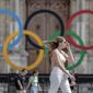 A woman passes by the Olympic rings at the City Hall in Paris, on July 25, 2022. Latvia is threatening to boycott next year’s Paris Olympics if athletes from Russia and its ally Belarus are allowed to take part after Russia&#39;s invasion of Ukraine. (AP Photo/Lewis Joly, File)