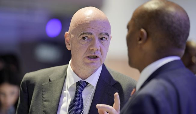 FIFA President Gianni Infantino, left, talks with South African mining businessman Patrice Motsepe, right, at the World Economic Forum in Davos, Switzerland, on Wednesday, Jan. 18, 2023. The annual meeting of the World Economic Forum is taking place in Davos from Jan. 16 until Jan. 20, 2023. (AP Photo/Markus Schreiber)