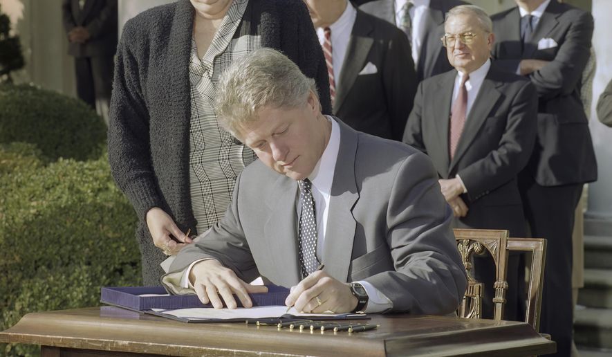 President Bill Clinton reaches for a pen as he signs the Family Leave Bill into law during a ceremony in the Rose Garden in Washington, Feb. 5, 1993. Looking over Clinton&#x27;s shoulder is Vicki Yandle of Marietta, Ga., whose husband lost his job when he took off to take care of their sick daughter. Behind the President are House Speaker Tom Foley of Wash., Sen. Ted Kennedy, D-Mass., and Rep. William Ford, D-Mich. President Joe Biden is playing host to former President Bill Clinton to mark the 30th anniversary of the Family and Medical Leave Act. It was the first piece of legislation that Clinton signed into law after taking office in 1993. (AP Photo/Greg Gibson, File)