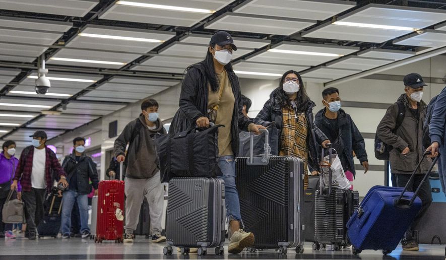 Travelers wearing face masks with their luggage head to the immigration counter at the departure hall at Lok Ma Chau station following the reopening of crossing border with mainland China, in Hong Kong, Sunday, Jan. 8, 2023. Hong Kong authorities announced Friday, Feb. 3, 2023, that they will lift a quota on the number of cross-border travelers with China and scrap mandatory COVID-19 PCR testing requirements as both places seek to drive economic growth. (AP Photo/Bertha Wang, File)