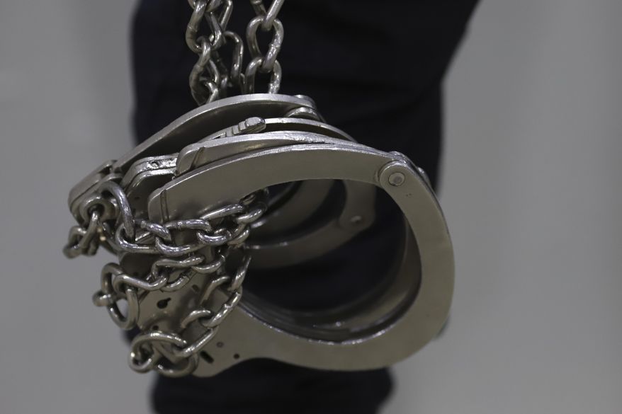 A prison guard holds handcuffs during a media tour of The Terrorism Confinement Center in Tecoluca, El Salvador, Thursday, Feb. 2, 2023. The "mega-prison" still under construction has a maximum capacity of 40,000 and is intended to imprison gang members, according to the government. (AP Photo/Salvador Melendez)