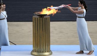 Greek actress Xanthi Georgiou, playing the role of High Priestess, lights the torch with the flame during the Olympic flame handover ceremony at Panathinean stadium in Athens, Greece, Tuesday, Oct. 19, 2021. Instead of arriving overland, the symbolic flame alighting the Paris 2024 Games will take to the seas from its birthplace in Greece, arriving aboard a three-masted tall ship in the French port of Marseille. Paris 2024 organizers announced the flame&#39;s journey Friday Feb.3, 2023 at City Hall in Marseille, a former Greek colony founded 2,600 years ago. (AP Photo/Petros Giannakouris, File)
