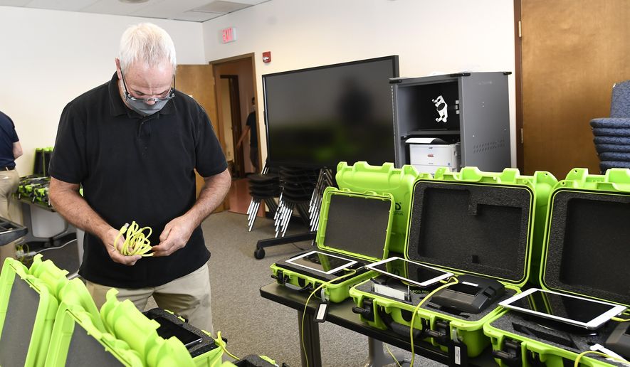 Mark Splonskowski assembles electronic poll book kits that voters will uses to sign in at polling locations at the Albany County Board of Elections building, Oct. 14, 2020, in Albany, N.Y. Attempts to develop the first-ever national standards for electronic voter rolls, the source of problems and hacking concerns in previous elections, may not be ready or available for wide use in time for the 2024 presidential election, concerning election experts. (AP Photo/Hans Pennink, File)