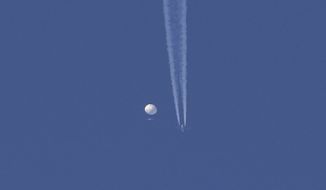 In this photo provided by Brian Branch, a large balloon drifts above the Kingston, N.C. area, with an airplane and its contrail seen below it. The United States says it is a Chinese spy balloon moving east over America at an altitude of about 60,000 feet (18,600 meters), but China insists the balloon is just an errant civilian airship used mainly for meteorological research that went off course due to winds and has only limited “self-steering” capabilities. (Brian Branch via AP)