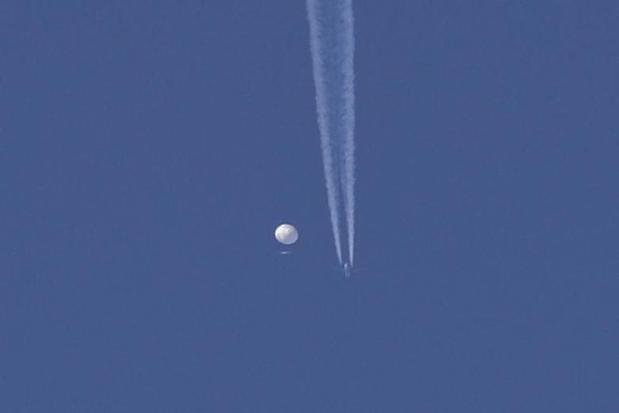 In this photo provided by Brian Branch, a large balloon drifts above the Kingstown, N.C. area, with an airplane and its contrail seen below it. (Brian Branch via AP)