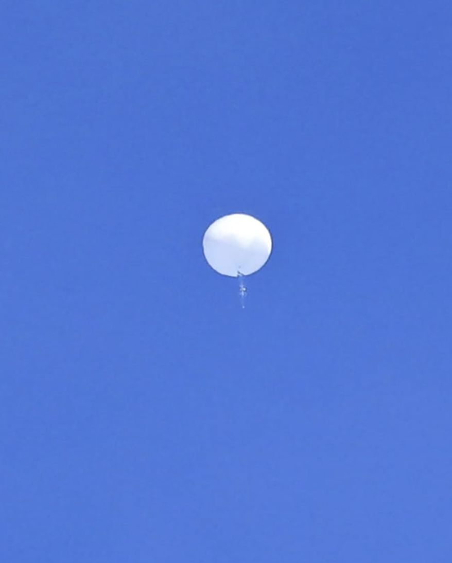 In this photo provided by Travis Huffstetler Photography, a large balloon drifts above the Atlantic Ocean, just off the coast of the Carolinas, Saturday, Feb. 4, 2023. The massive white orb that drifted across U.S. airspace this week and was shot down by the Air Force over the Atlantic on live television Saturday triggered a diplomatic maelstrom and blew up on social media. (Travis Huffstetler Photography via AP)