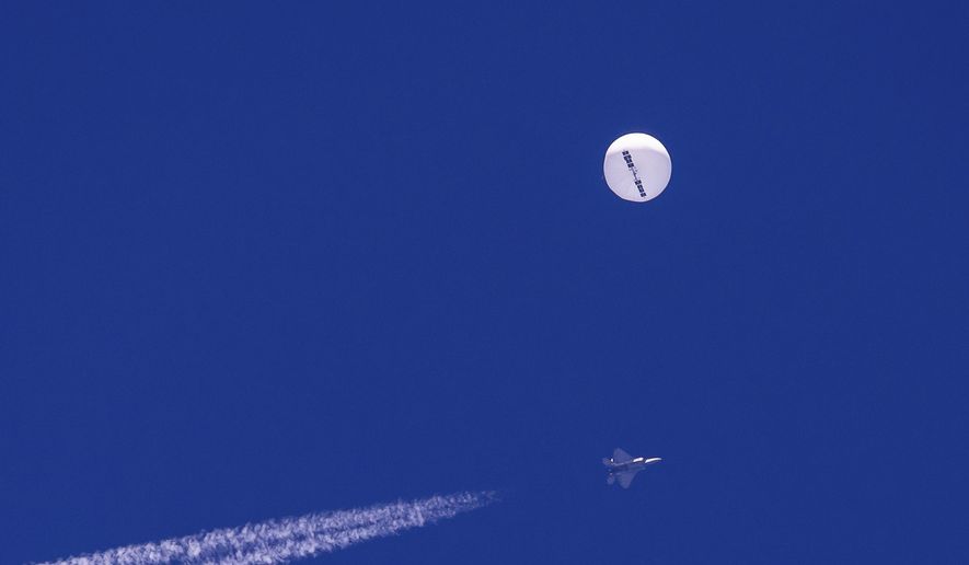 In this photo provided by Chad Fish, a large balloon drifts above the Atlantic Ocean, just off the coast of South Carolina, with a fighter jet and its contrail seen below it, Saturday, Feb. 4, 2023. The balloon was struck by a missile from an F-22 fighter just off Myrtle Beach, fascinating sky-watchers across a populous area known as the Grand Strand for its miles of beaches that draw retirees and vacationers. (Chad Fish via AP)