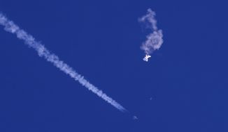 In this photo provided by Chad Fish, the remnants of a large balloon drift above the Atlantic Ocean, just off the coast of South Carolina, with a fighter jet and its contrail seen below it, Saturday, Feb. 4, 2023. The downing of the suspected Chinese spy balloon by a missile from an F-22 fighter jet created a spectacle over one of the state&#39;s tourism hubs and drew crowds reacting with a mixture of bewildered gazing, distress and cheering. (Chad Fish via AP)