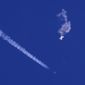 In this photo provided by Chad Fish, the remnants of a large balloon drift above the Atlantic Ocean, just off the coast of South Carolina, with a fighter jet and its contrail seen below it, Saturday, Feb. 4, 2023. The downing of the suspected Chinese spy balloon by a missile from an F-22 fighter jet created a spectacle over one of the state&#39;s tourism hubs and drew crowds reacting with a mixture of bewildered gazing, distress and cheering. (Chad Fish via AP)