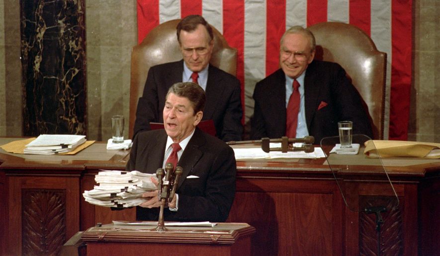 This Jan. 25, 1988 file photo shows President Ronald Reagan holding up 14-pound continuing resolution for the budget, part of a total package weighing 43-pounds, which the president said was two months late from Congress, during his State of the Union address on Capitol Hill in Washington.  Vice President George H.W. Bush, left, and House Speaker James Wright of Texas listen behind him.  (AP Photo/Bob Daugherty, File)