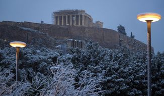 Snow covers a tree in central Athens with the ancient Parthenon temple on the Acropolis hill seen in the background, in Athens, on Monday, Feb. 6, 2023. A cold snap sweeping across southern Greece has caused blackouts, highway closures, and service disruptions. Schools were closed in Athens, along with court houses and multiple services. (AP Photo/Thanassis Stavrakis)