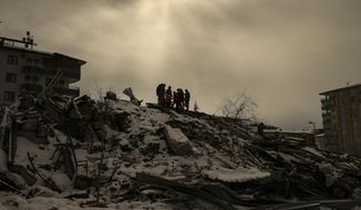 People try to reach people trapped under the debris of a collapsed building in Malatya, Turkey, Tuesday, Feb. 7, 2023. Search teams and aid are pouring into Turkey and Syria as rescuers working in freezing temperatures dig through the remains of buildings flattened by a magnitude 7.8 earthquake. (AP Photo/Emrah Gurel)