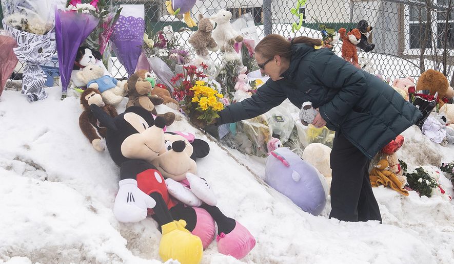 A woman places flowers at the site of a day care center in Laval, Quebec, Thursday, Feb. 9, 2023, where a bus crashed into the building killing two children. (Graham Hughes/The Canadian Press via AP)