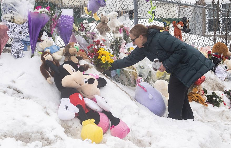 A woman places flowers at the site of a day care center in Laval, Quebec, Thursday, Feb. 9, 2023, where a bus crashed into the building killing two children. (Graham Hughes/The Canadian Press via AP)