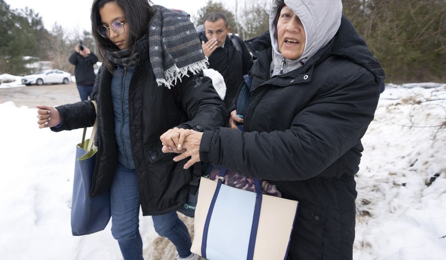 A family of asylum seekers from Columbia crosses the border at Roxham Road into Canada on Thursday, Feb. 9, 2023, in Champlain, N.Y. (Ryan Remiorz/The Canadian Press via AP)
