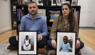 Bryan and Julie Hanlon hold photos of their adopted Haitian children, Gina, left, and Peterson, in a play area of their home in Washington, Tuesday, Feb. 7, 2023. They became the legal parents of the siblings in 2022 and fear they won&#x27;t be able to secure their passports and fly them out of Haiti. (AP Photo/Cliff Owen)